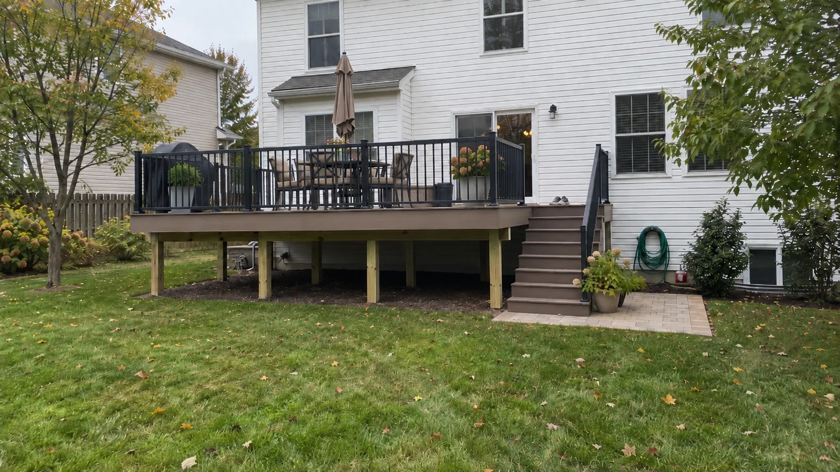 A raised composite deck with black railings seen from the lawn